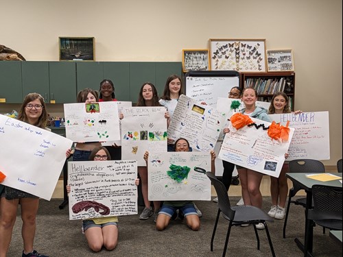 Girls hold up their poster projects at the Scout Senior Eco Explorer event