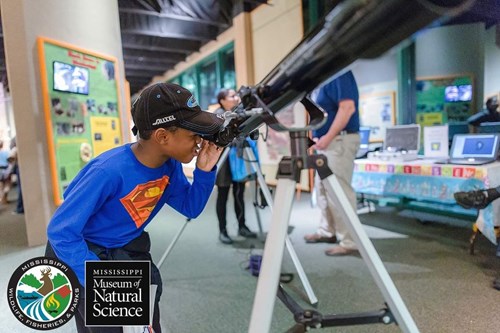 Boy looks through a telescope at the Science Makers event