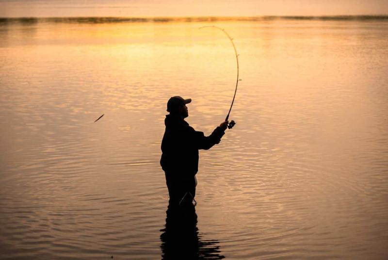 Man fishing in the water at sunset