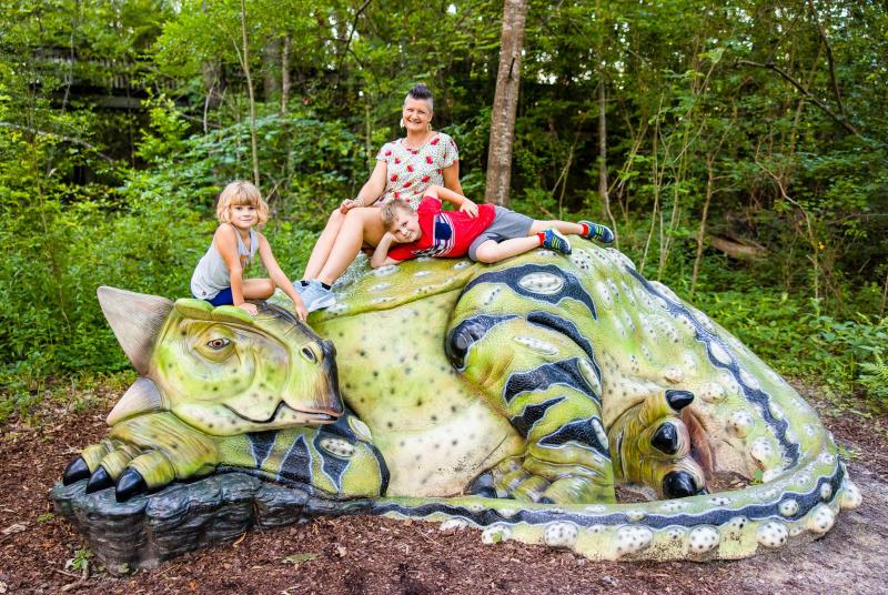 Family sits atop a green dinosaur sculpture